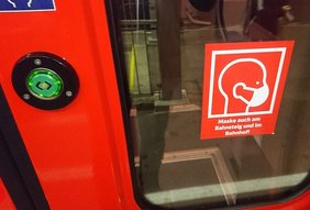 Tür einer S-Bahn mit Hinweisschild "Maske auch "am Bahnsteig und im Bahnhof